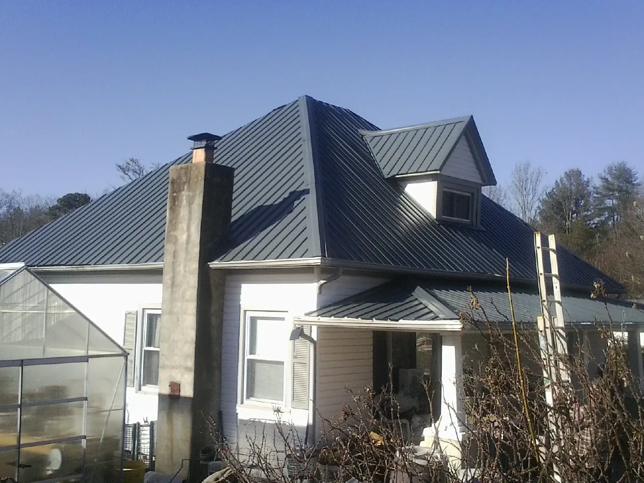 Dark blue standing seam metal roof on a white farmhouse with dormer — Slate & Tile Roof Repair by Roofing Brothers in Connersville