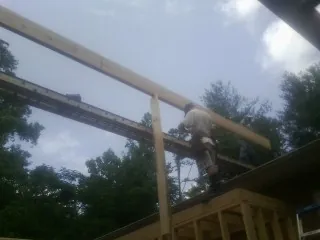 Carpenter setting a ridge beam over a new addition frame — Ice Dam Removal by Roofing Brothers in Connersville