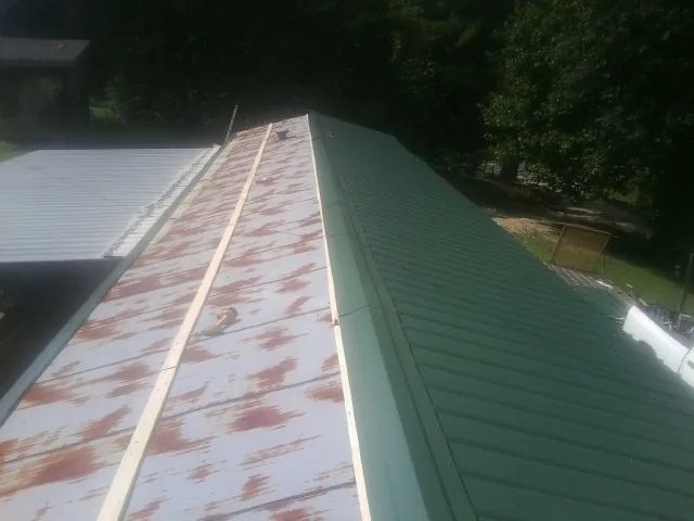 Old rusted panels beside newly installed green metal roofing — Wind Damage Roof Repair by Roofing Brothers in Connersville
