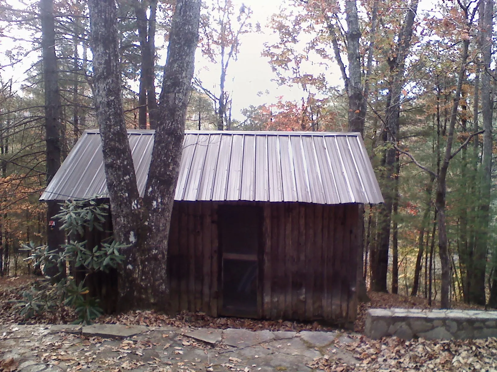 New metal gable roof on a small log shed among the trees in Connersville
