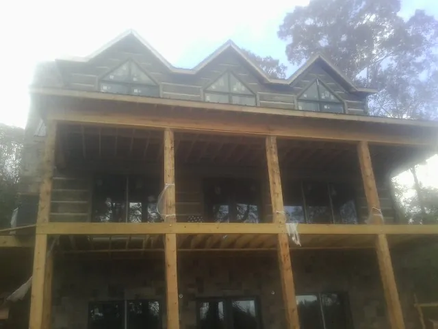 Dormers and porch framing on a large log home under construction — Roof Coating work by our crew in Connersville