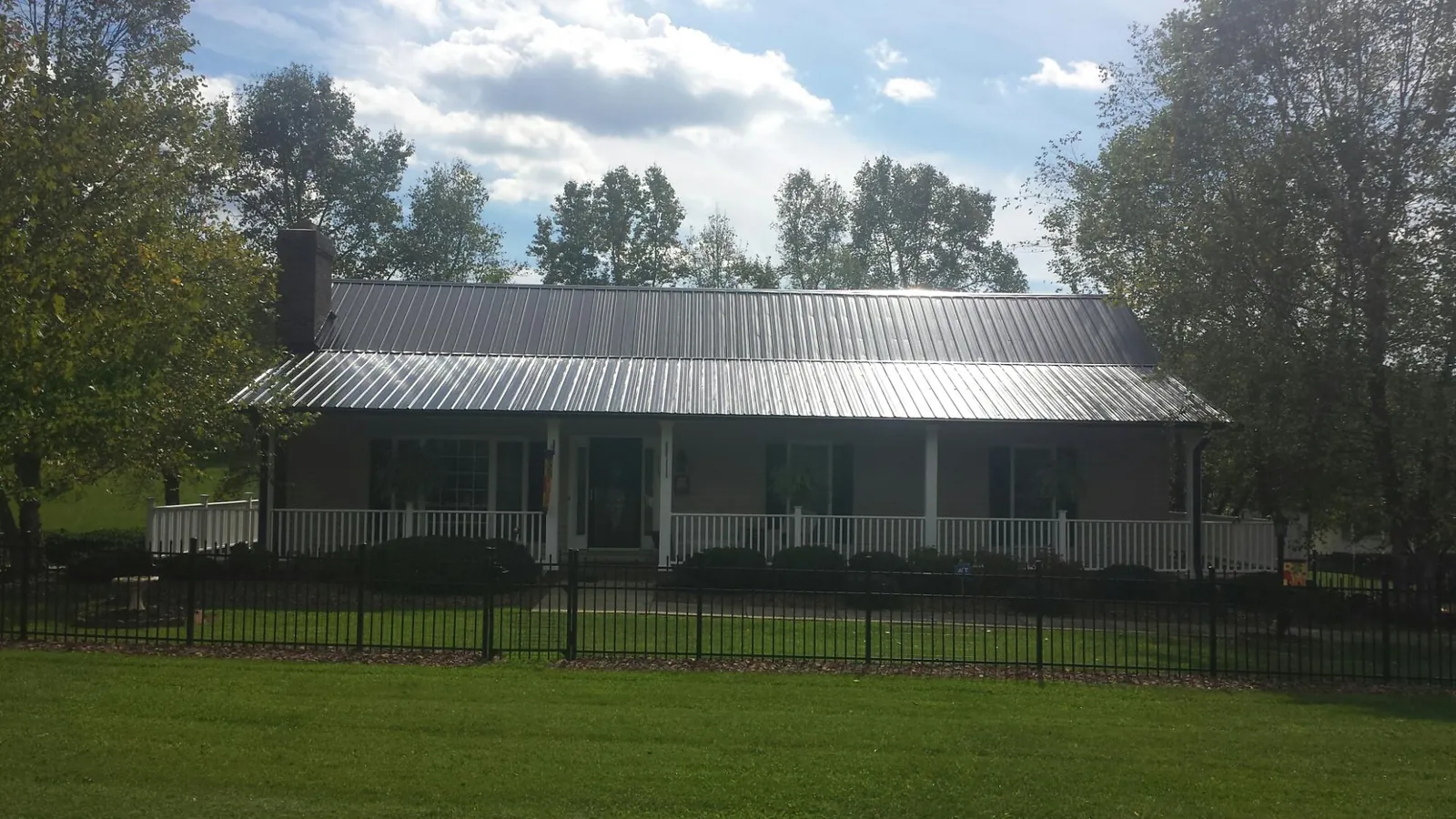 Gray metal roof on a brick ranch with a full width front porch — Gutter Guard Installation work by our crew in Connersville