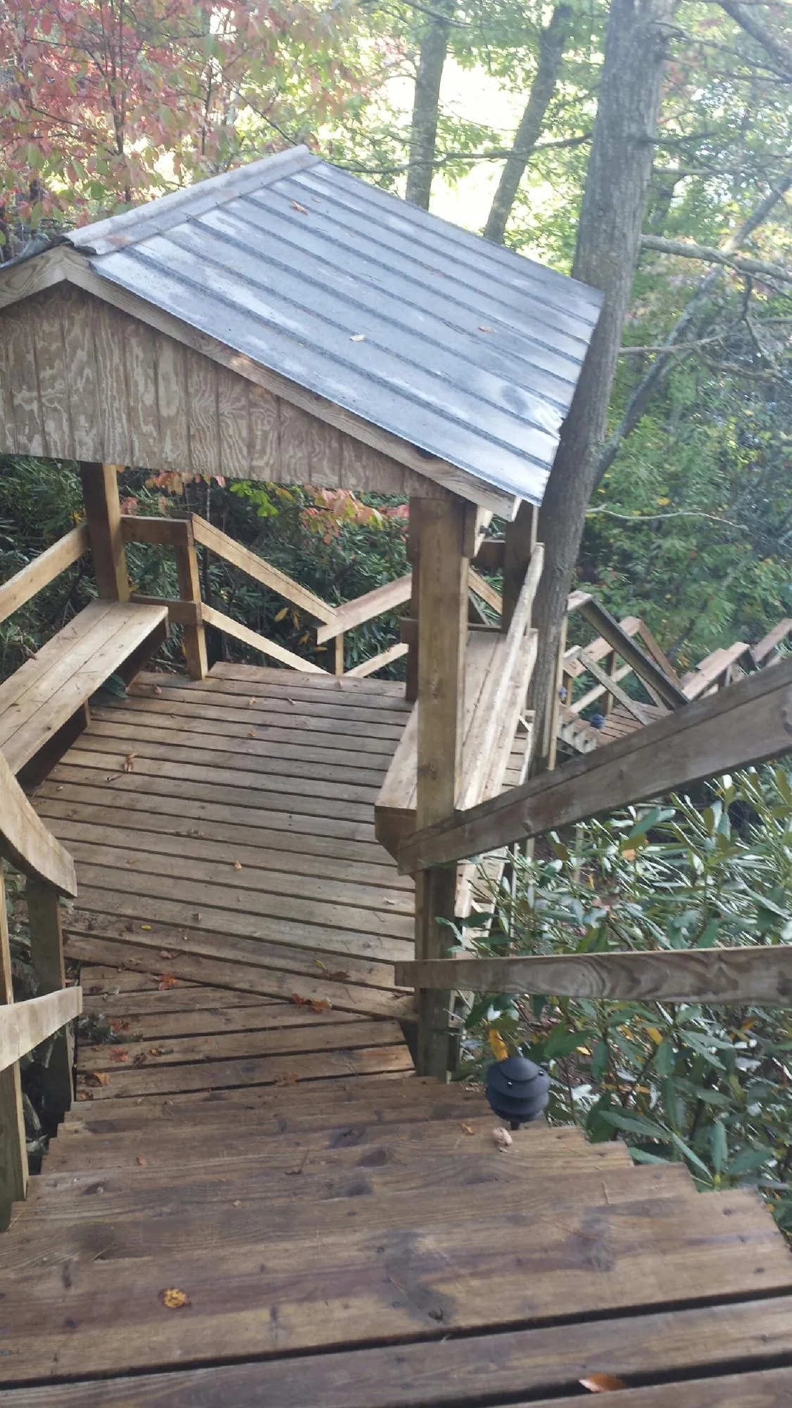 Metal roofed shelter over wooden steps on a wooded walkway — Skylight Repair & Installation work by our crew in Connersville
