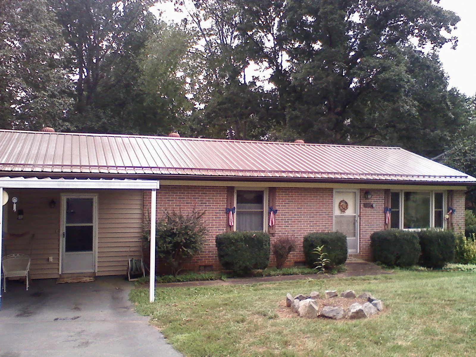 Bronze metal roof and carport on a brick ranch home — Roof Repair work by our crew in Connersville
