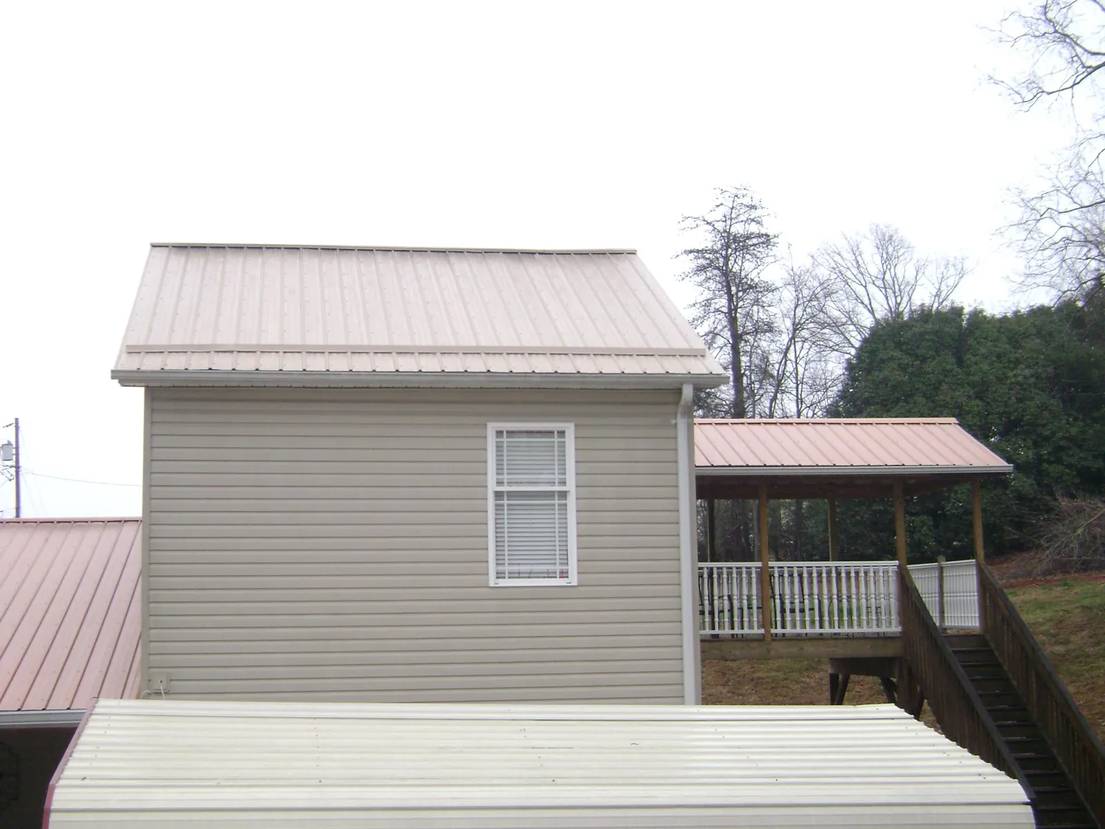 Tan metal roofs on a two story addition and attached porch, from a Roof Replacement job in Connersville