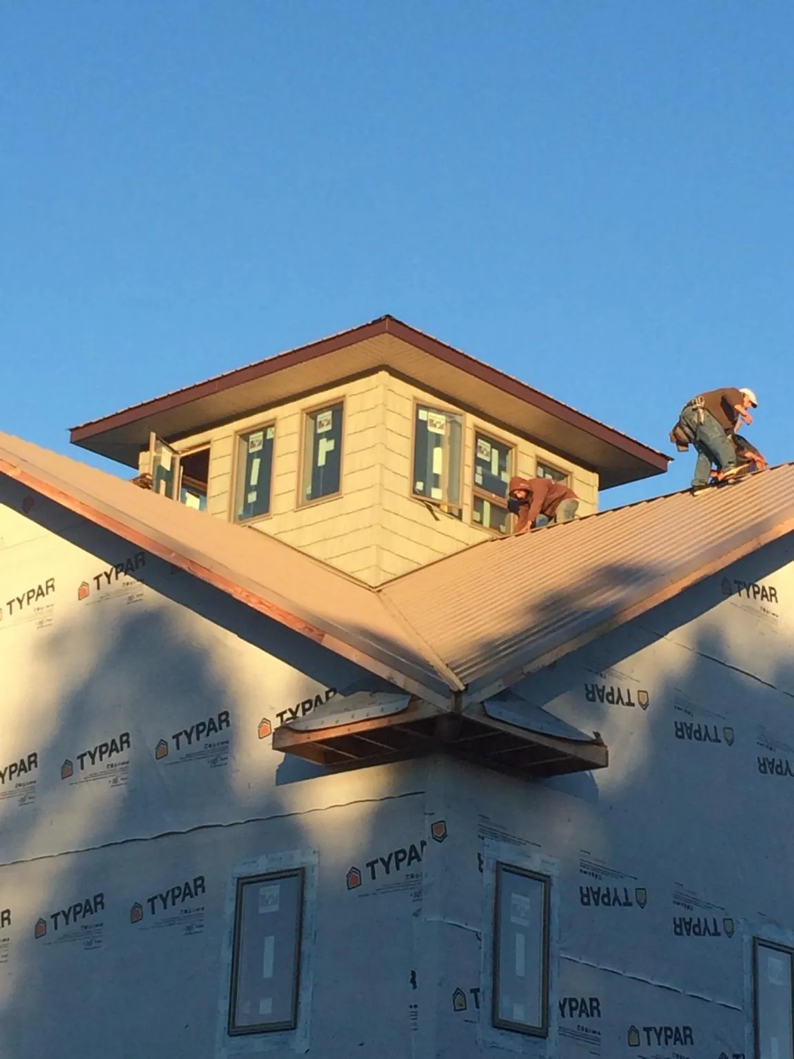 Roofers working around a rooftop cupola on a new metal roof at sunset — Roof Waterproofing in Connersville by Roofing Brothers